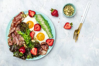 Ketojenik diyet yiyecekler, avokadolu kızarmış yumurta pastırması, çilek ve hafif arkaplanda taze salata. Sağlıklı yemek konsepti, uzun afiş formatı. en üstteki görünüm.