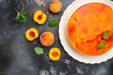Tasty cheesecake with fruit peaches, peache jelly, jam on a dark background.