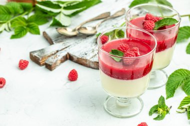 Küçük kavanozlarda krema soslu böğürtlen tatlısı. İtalyan tatlısı. Hafif arka planda ahududu reçelli ahududu panna cotta. metin için yer, üst görünüm.