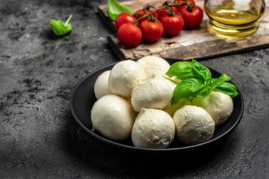 Peynir koleksiyonu, koyu arkaplanda taze fesleğen yapraklı beyaz İtalyan peynirli mozzarella topları. Uzun afiş biçimi. en üstteki görünüm.