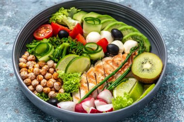 Izgara tavuk, avokado, kuşkonmaz, nohut, brokoli, turp, salatalık, domates, zeytin mozzarella budha kasesi koyu arka planda, üst görünümde lezzetli dengeli gıda konsepti.