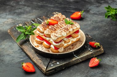 Taze çilekli ev yapımı tiramisu keki, mascarpone ve naneli. Koyu arkaplanda tiramisu tabakası var. Lezzetli. Fırında tiramisu yok..