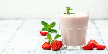 Meyveli smoothie. Çilekli smoothie ya da meyveli milkshake ve beyaz arka planda cam kavanozda yoğurt. Sağlıklı vejetaryen içeceği. Uzun afiş biçimi. en üstteki görünüm.