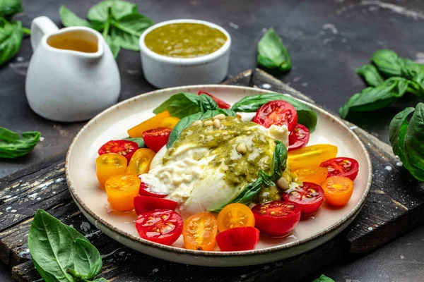 Salad burrata cheese tomatoes and green pesto. Delicious balanced food concept. superfood concept. Healthy, clean eating. Vegan or gluten free diet. top view.