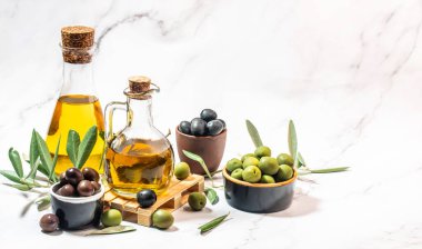 İki cam kapta zeytinyağı ve hafif arka planda zeytin meyveleri.