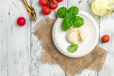 burrata cheese tomatoes on white plate on a light background. recipe top view.