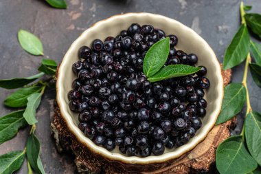 Superfoods antioxidant of indian mapuche. Bowl of fresh maqui berry on dark background, top view.