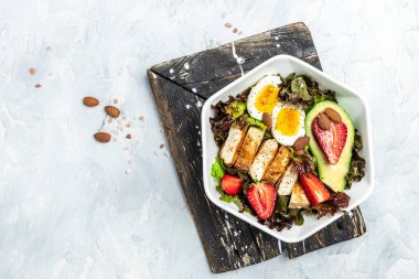 Sağlıklı besleyici paleo keto kahvaltı diyeti iki yumurta, avokado, ızgara tavuk fileto, fındık, çilek ve taze salata. Keto kahvaltısı ya da öğle yemeği. metin için yer, üst görünüm.