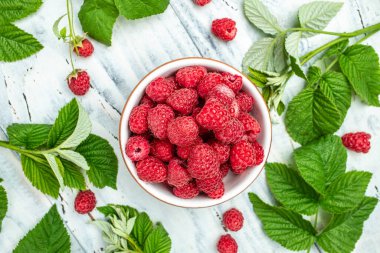 Beyaz ahşap arka planda kırmızı ahududular kasede. Organik ahududu. Kırmızı dut. Üst Manzara. metin için yer.