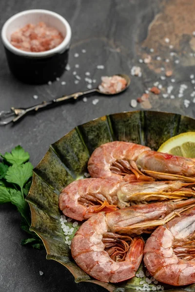 Seafood. Red Argentine shrimps with salt and lemon, Wild shrimps, ocean jumbo shrimps on a dark background. vertical image. top view. place for text.