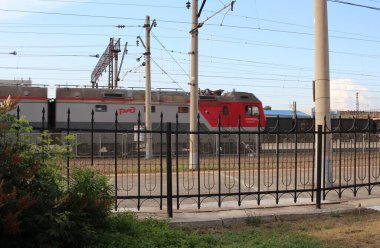 Rusya, Novosibirsk 02.08.2021: bir yolcu treni demiryolu rayları üzerinden çitin arkasından geçiyor.