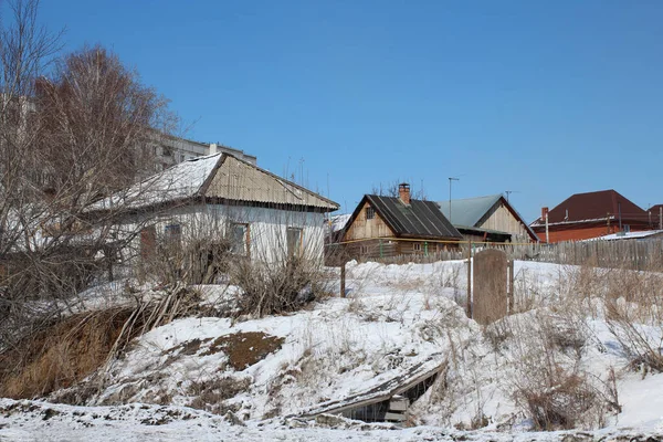 村には 凍った川のほとりに白い漂流の中で冬のシベリアの村の家に雪に覆われた木造住宅がたくさんあります — ストック写真