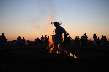 Russia, Novosibirsk 10.07.2021: pagan religious round dance at the Ivan Kupala Solstice in Siberia, people jump over the fire in the bonfire