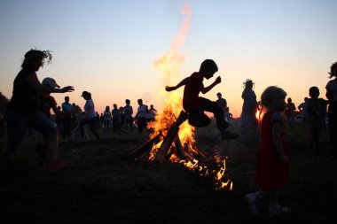 Russia, Novosibirsk 10.07.2021: pagan religious round dance at the Ivan Kupala Solstice in Siberia, people jump over the fire in the bonfire