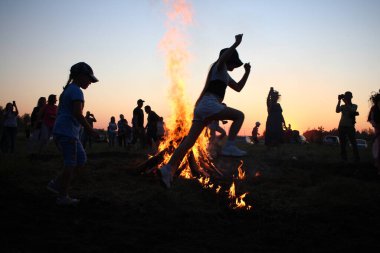 Russia, Novosibirsk 10.07.2021: pagan religious round dance at the Ivan Kupala Solstice in Siberia, people jump over the fire in the bonfire