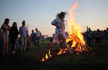 Russia, Novosibirsk 10.07.2021: pagan religious round dance at the Ivan Kupala Solstice in Siberia, people jump over the fire in the bonfire