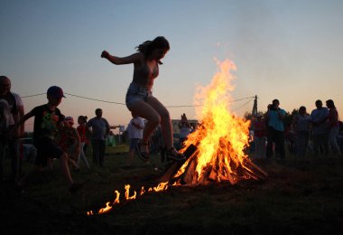 Russia, Novosibirsk 10.07.2021: pagan religious round dance at the Ivan Kupala Solstice in Siberia, people jump over the fire in the bonfire