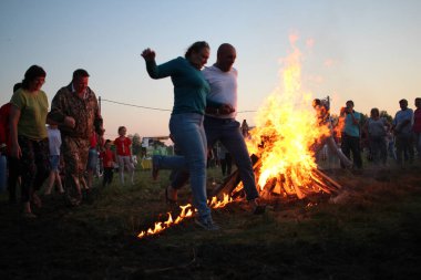 Russia, Novosibirsk 10.07.2021: pagan religious round dance at the Ivan Kupala Solstice in Siberia, people jump over the fire in the bonfire