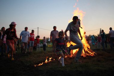 Russia, Novosibirsk 10.07.2021: pagan religious round dance at the Ivan Kupala Solstice in Siberia, people jump over the fire in the bonfire