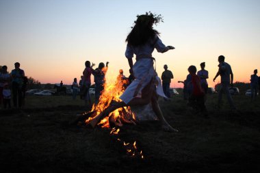 Russia, Novosibirsk 10.07.2021: pagan religious round dance at the Ivan Kupala Solstice in Siberia, people jump over the fire in the bonfire