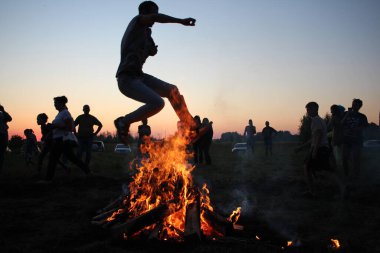 Russia, Novosibirsk 10.07.2021: pagan religious round dance at the Ivan Kupala Solstice in Siberia, people jump over the fire in the bonfire