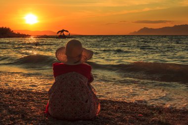 Thinking Woman sit in the sunset on the beach clipart