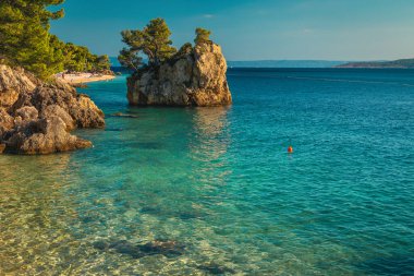 Temiz deniz ve sahildeki görkemli kaya adasıyla göz kamaştırıcı bir manzara. Dalmaçya, Brela, Makarska Riviera, Hırvatistan ve Avrupa 'nın en iyi ziyaret edilen plajlarından biri