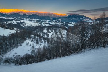 Yüksek karlı dağlarla baş döndürücü kış şafağı manzarası. Arka planda büyülü gündoğumu ve karlı dağ sırtı, Piatra Craiului dağları, Karpatlar, Romanya, Avrupa
