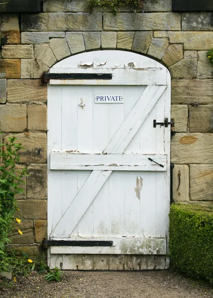 Stare białe drewniane drzwi na ogród otoczony murem — Zdjęcie stockowe