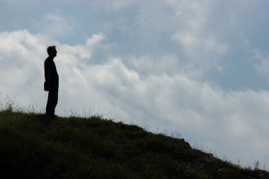 bir tepe üzerinde duran bir adam silüeti