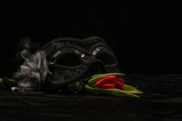 Maschera in maschera con fiore rosso su sfondo nero — Foto Stock