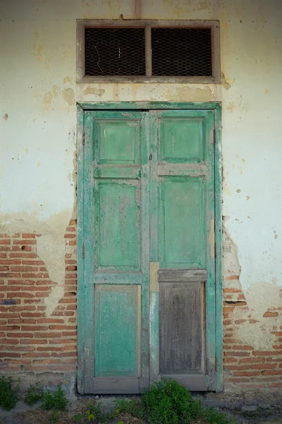 Green wooden doors is closed on grunge brick wall. — Stock Photo, Image