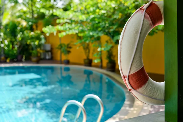 Lifebuoy pendurado em um feixe de madeira na piscina — Fotografia de Stock