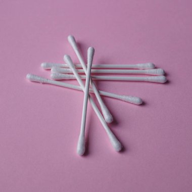 Pembe arka planda pamuk çubukları, kozmetik ürünleri ve hijyen. 