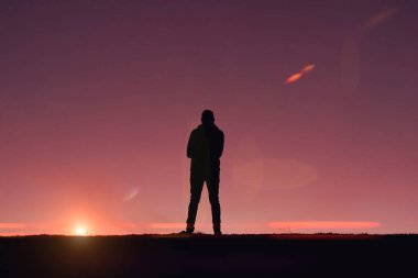 Yazın günbatımı geçmişiyle dağda yürüyüş yapan bir adam. 