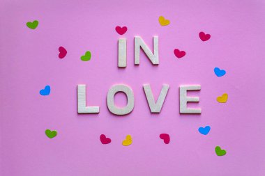 Aşk sözcüğüyle pembe arka planda ahşap harflerle, Sevgililer Günü 