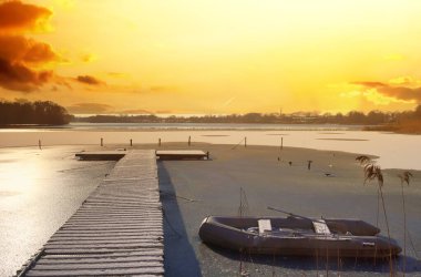 Güzel gün batımı kışı kar ve buzla dolu bir göle vuruyor.