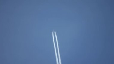 Gökyüzünde yükseklerde uçan jet uçağı açık mavi gökyüzünde kontrastlar bırakır..