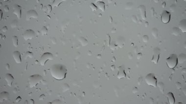 Yakın planda bir pencereden süzülen yağmur damlalarının süreleri.