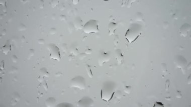 Yakın planda bir pencereden süzülen yağmur damlalarının süreleri.