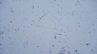 Yakın planda bir pencereden süzülen yağmur damlalarının süreleri.