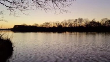 Gün batımında yansıtıcı su yüzeyi olan romantik bir göl manzarası