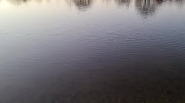 Gün batımında yansıtıcı su yüzeyi olan romantik bir göl manzarası