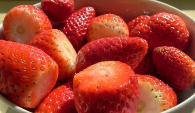 Taze çilekler beyaz bir kaseye dökülür.