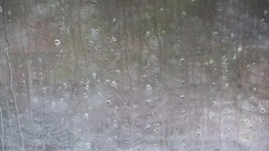 Yakın planda pencereden aşağı akan yağmur damlaları.