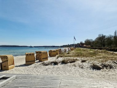 Eckernfotte, Almanya - 21. Nisan 2022: Eckernfotte 'deki Baltık Denizi sahilinde plaj sandalyeleri ve ziyaretçilerle dolu bir yaz günü