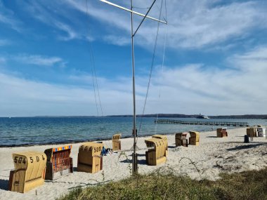 Eckernfotte, Almanya - 21. Nisan 2022: Eckernfotte 'deki Baltık Denizi sahilinde plaj sandalyeleri ve ziyaretçilerle dolu bir yaz günü