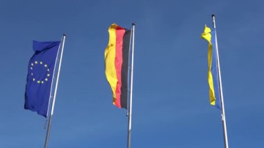 Ukrayna, Almanya ve Avrupa Birliği bayrakları mavi gökyüzüne karşı yan yana dalgalanıyor.