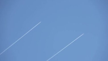 Two military jeys flying high in the sky leaving contrails in the clear blue sky