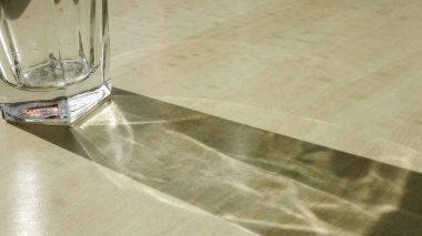 Ahşap bir masanın üzerinde yakıcı ışık efektleri olan bir bardak içmek.